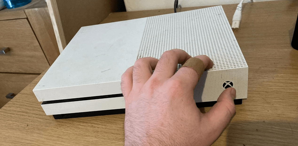 A hand pressing the xbox power button